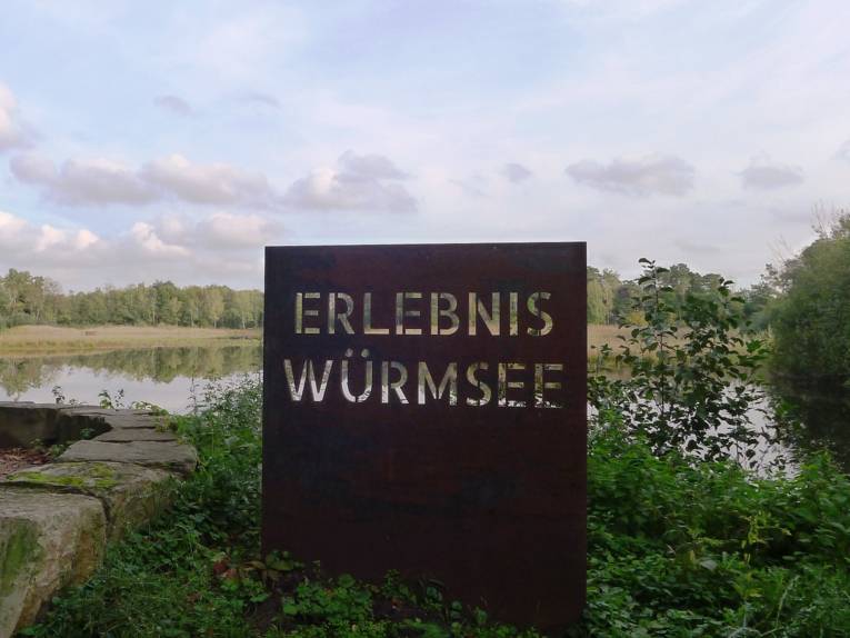Am Ufer eines See steht eine Metallskulptur mit den Buchstaben ERLEBNIS WÜRMSEE.